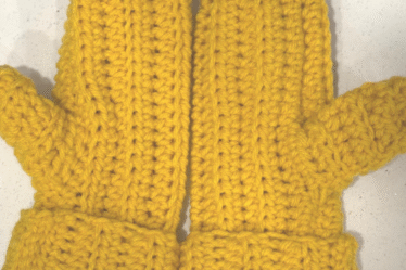 Handmade crochet ribbed mittens displayed flat, showing the textured ribbing pattern for an easy beginner crochet project with a free video tutorial, A pair of crochet ribbed mittens made with worsted weight yarn, promoting a simple beginner-friendly pattern with a free video tutorial. Crochet ribbed mittens in textured ribbing with easy beginner pattern and free video tutorial.