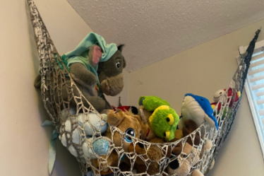 Crochet toy hammock hanging neatly with plush toys inside, showcasing a handmade storage solution pattern perfect for organizing stuffed animals in a nursery or playroom.